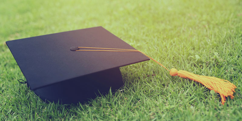 Mortar Board and tassel laying on green grass