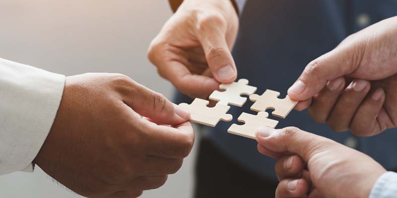 people hold in hand puzzle pieces to show collaboration